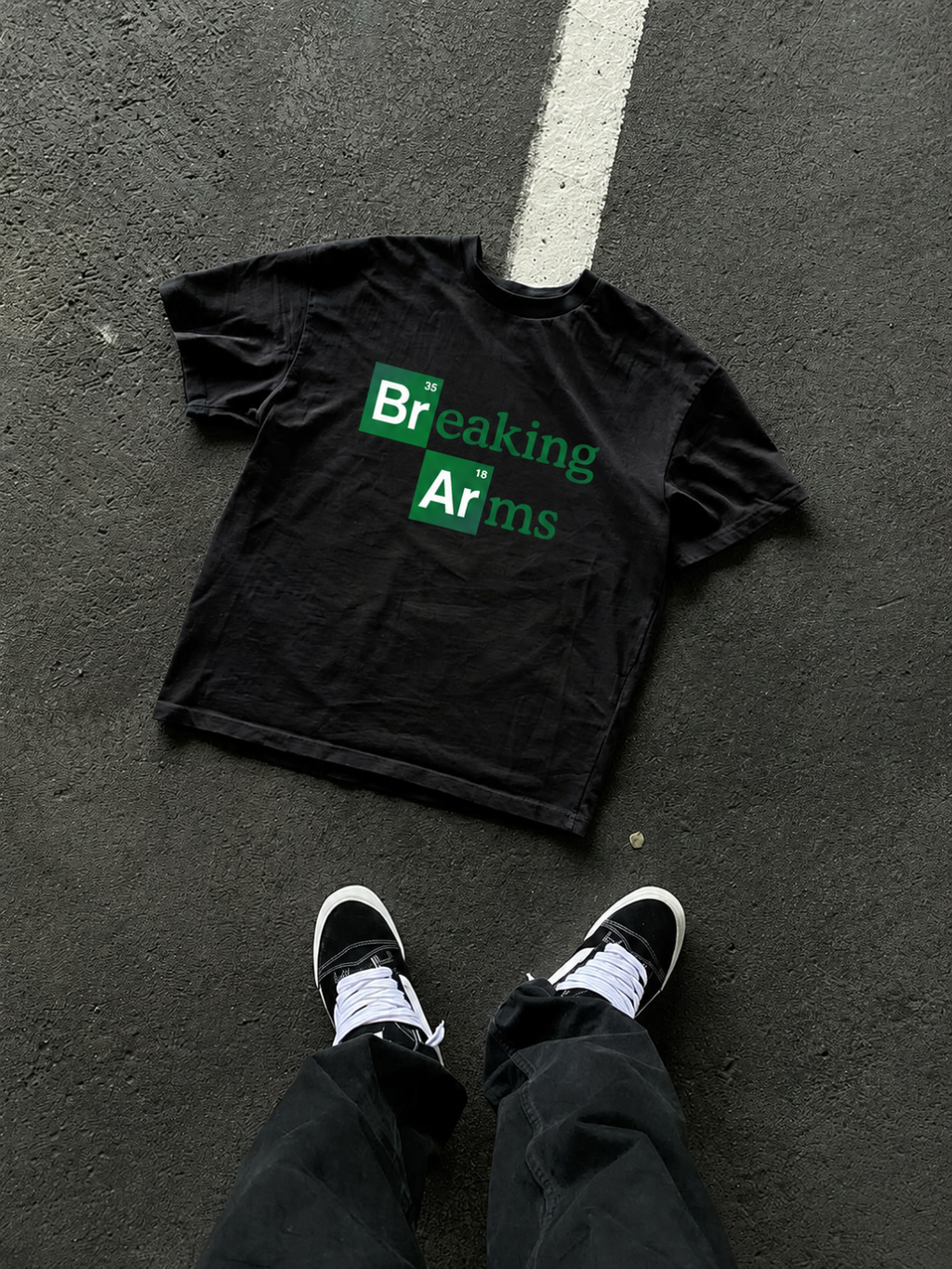 Black Breaking Arms tee from BJJ World, laid on asphalt and shot from above.