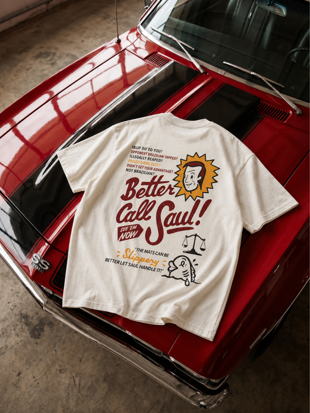 Cream Better Call Saul tee from BJJ World, back print laid on a red sports car.