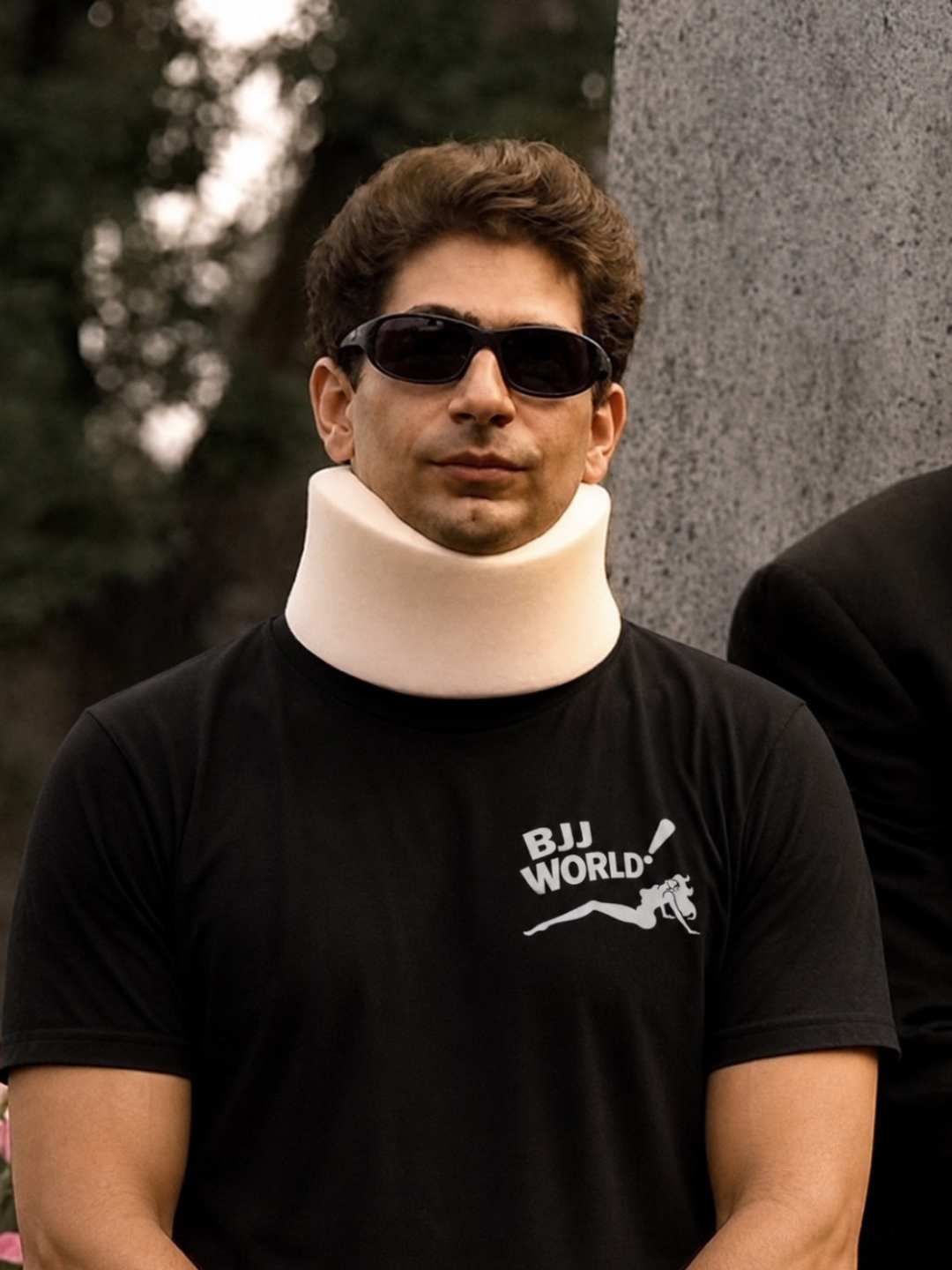 Black tee from BJJ World with a small chest logo, worn with a foam neck brace.