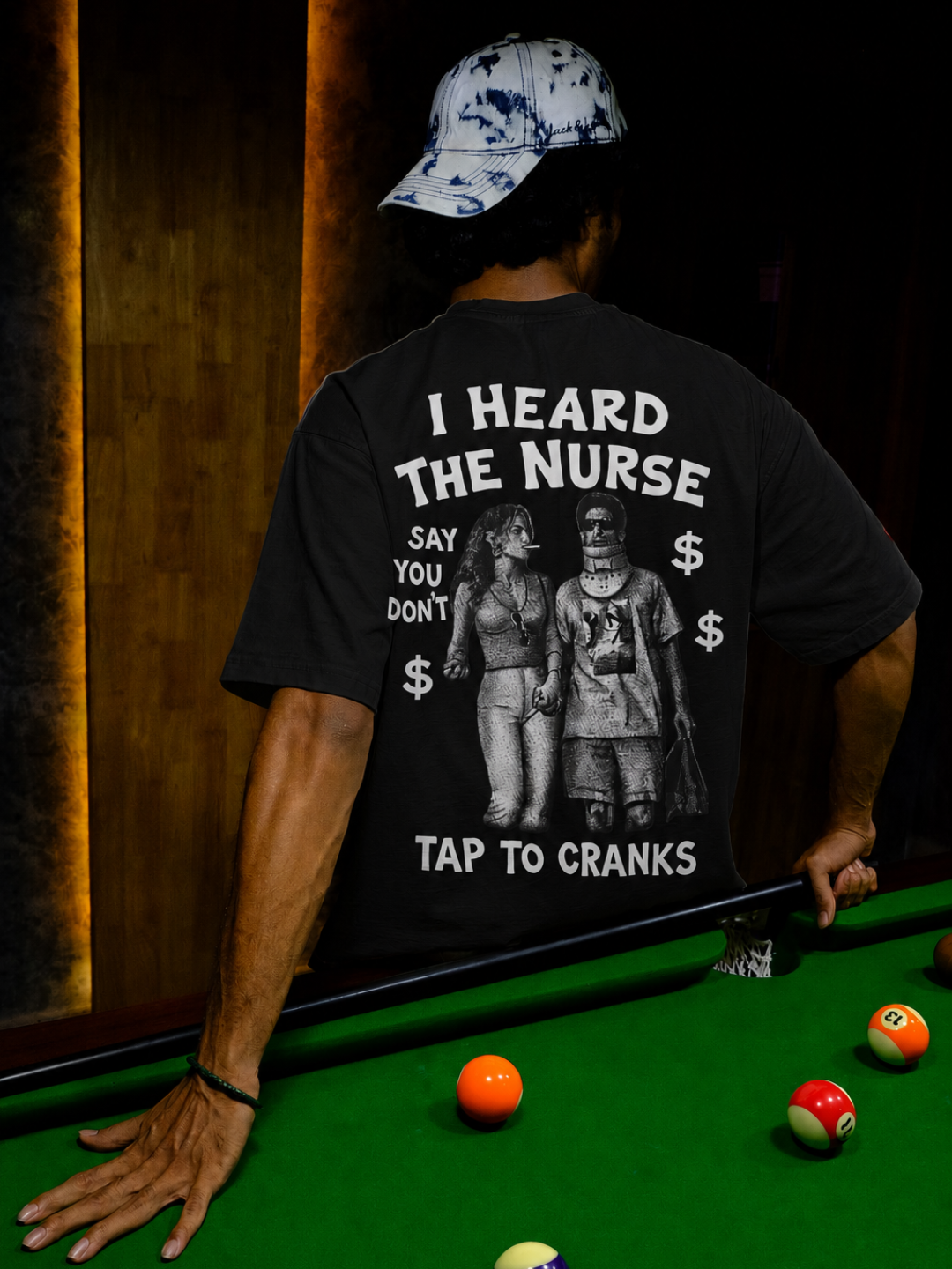 Black I Heard The Nurse tee from BJJ World, back print and cap at a pool table.