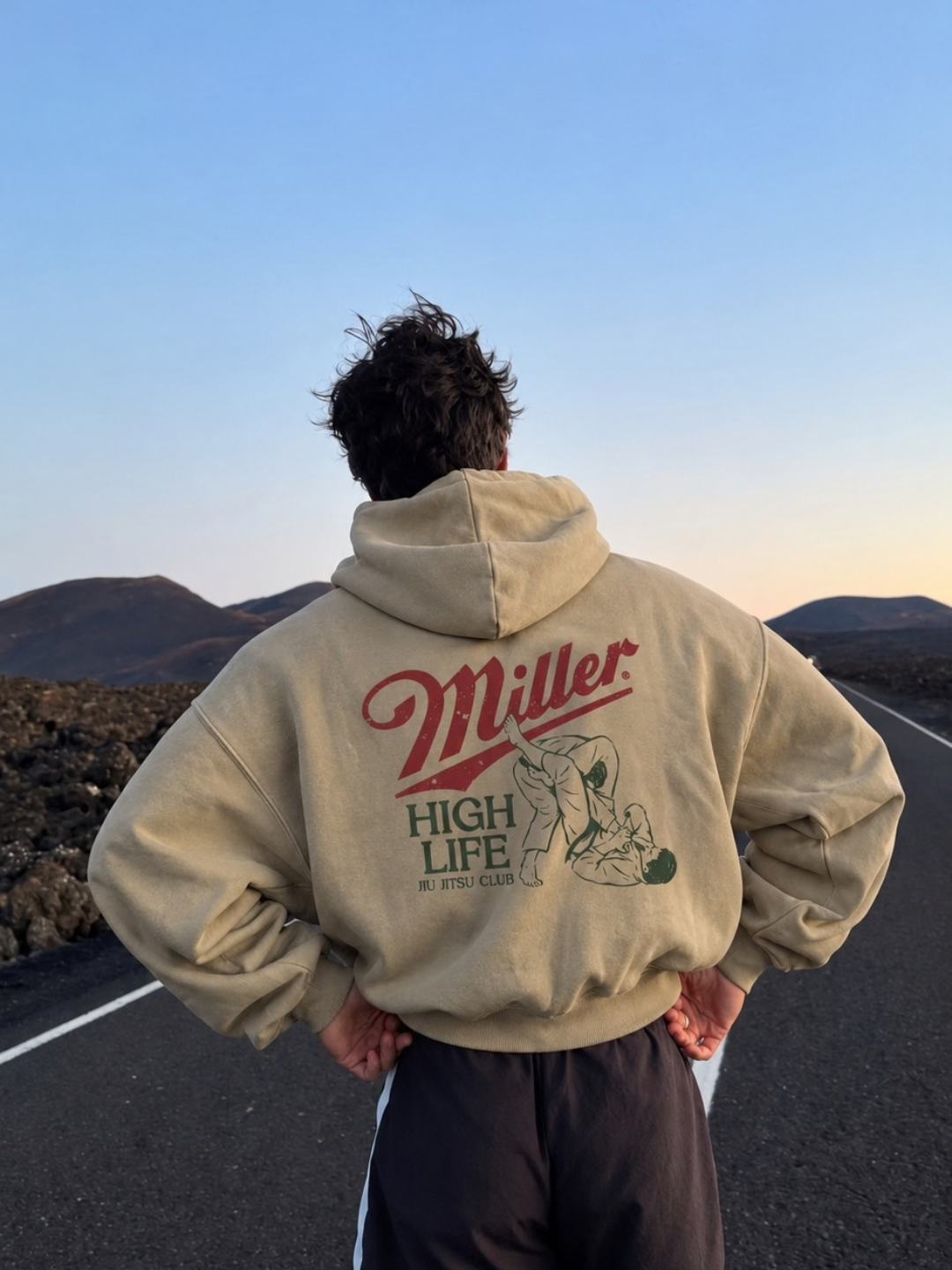 Tan Miller Jiu Jitsu Club hoodie from BJJ World, back print worn on an open road at dusk.