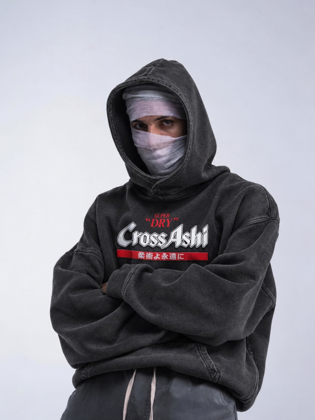 Washed black CrossAshi hoodie from BJJ World, worn hood up with the front label print.