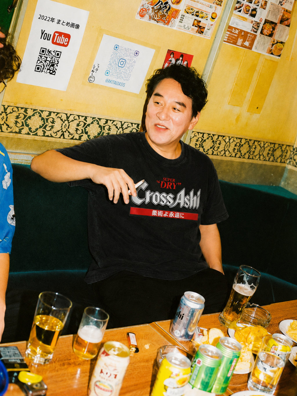 Washed black CrossAshi tee from BJJ World, worn at a table of drinks.