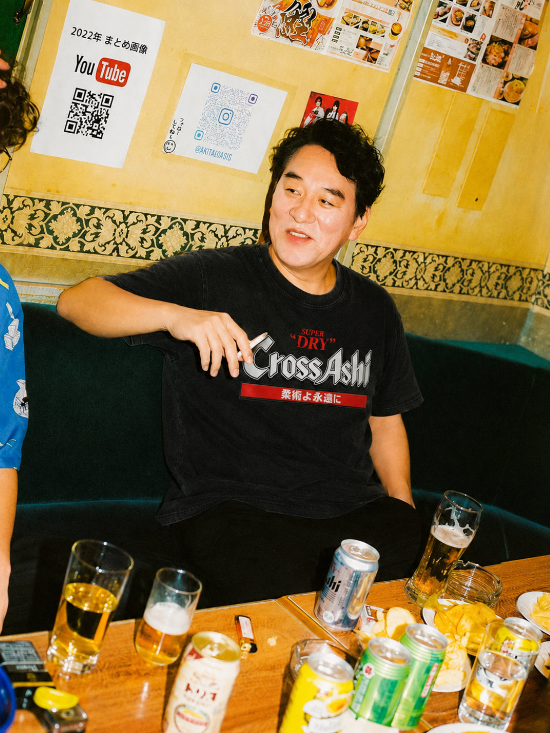 Washed black CrossAshi tee from BJJ World, worn at a table of drinks.